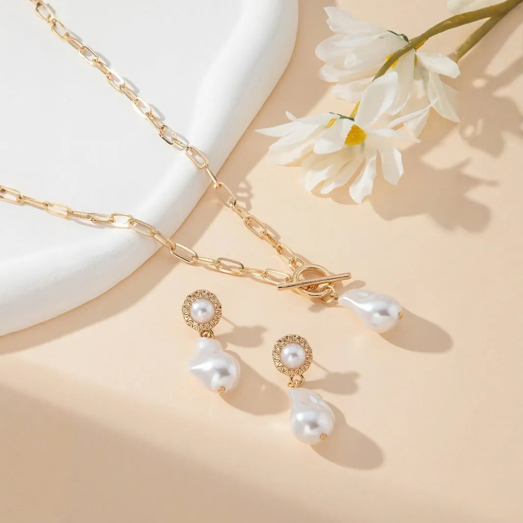 Gold-tone baroque pearl pendant necklace and matching stud earrings set on a white background.