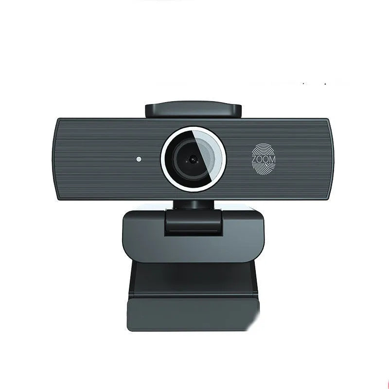 Black USB webcam with magnetic privacy cover on a desktop next to a laptop.