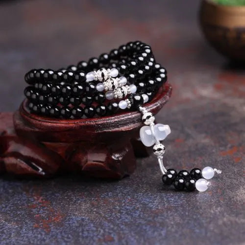 Black agate bracelet with 108 geometric beads and number details on a wrist.