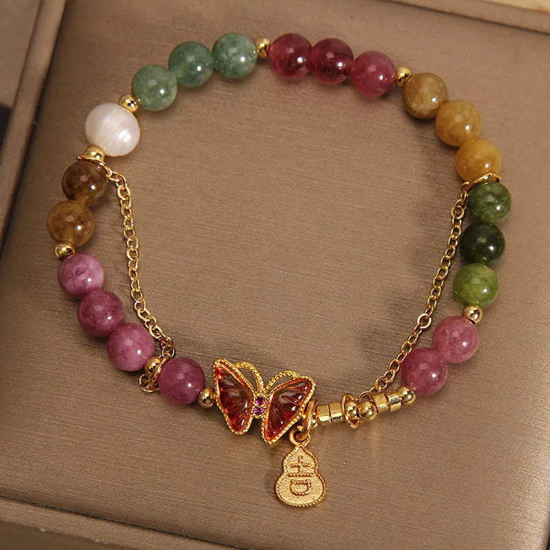 Close-up of an agate butterfly bracelet with a tourmaline-coloured gourd charm on a model's wrist.
