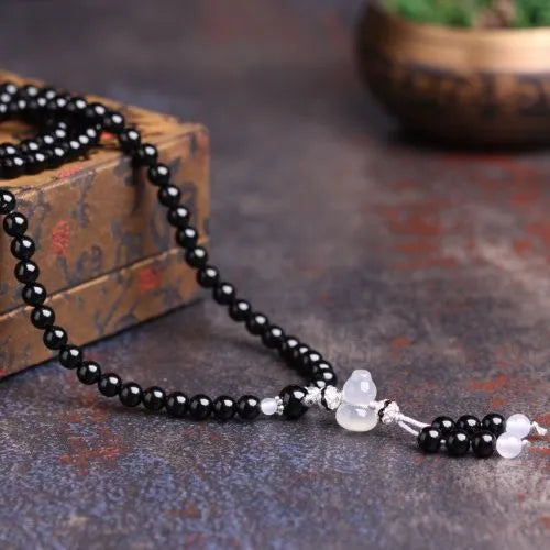 Black agate bracelet with 108 geometric beads and number details on a wrist.