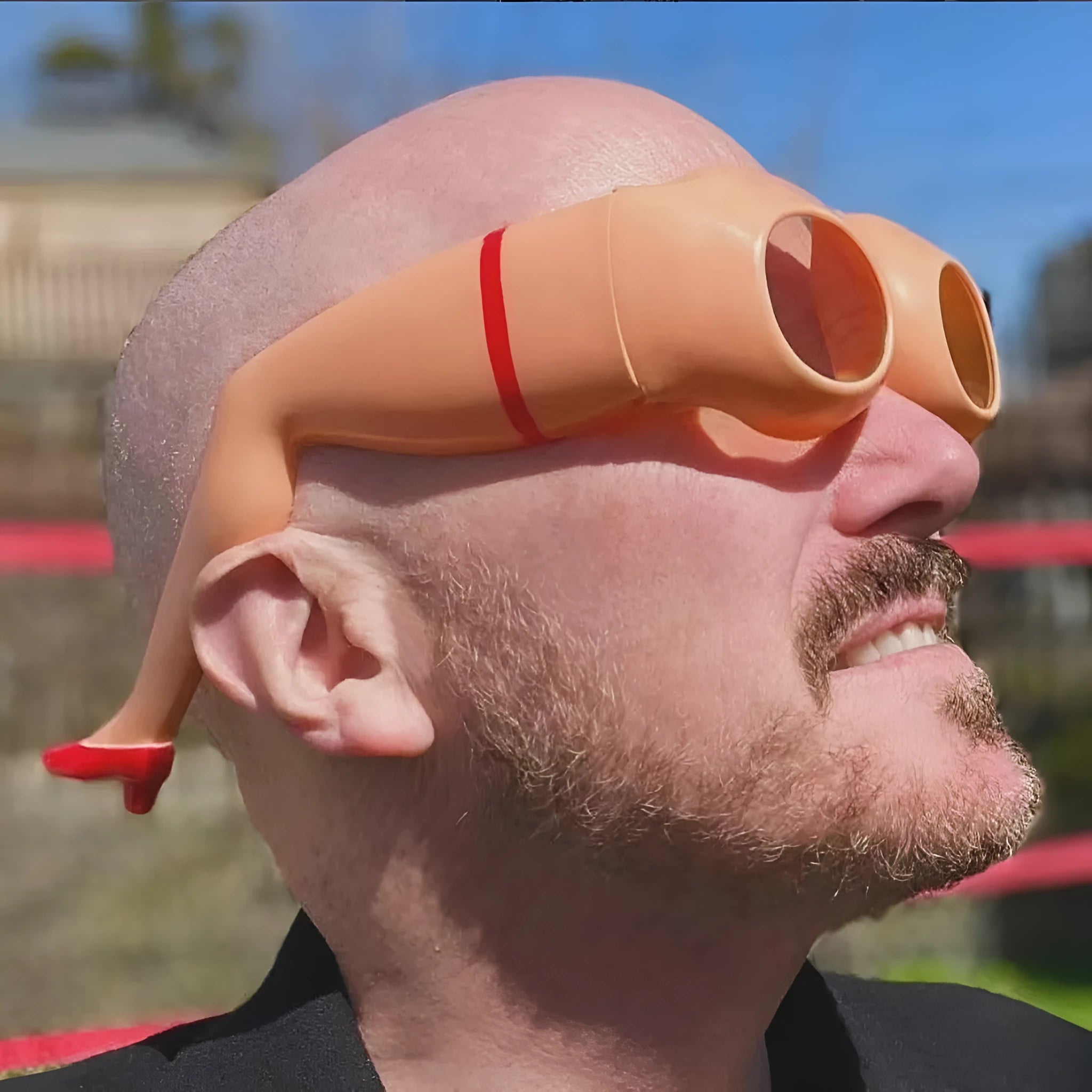 Orange novelty sunglasses with a unique leg hip style design on a white background.