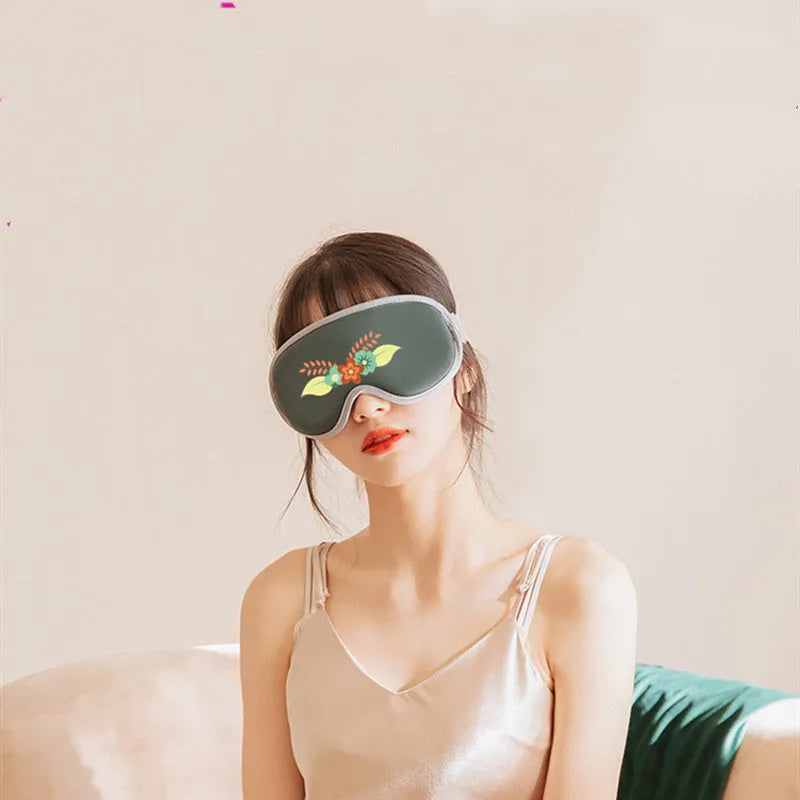 Pink and green portable eye massage goggles with USB cable on a grey background.