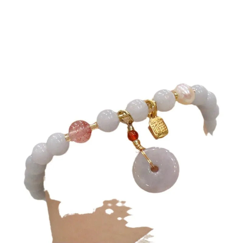 Gold plated bracelet with a detailed artificial crystal charm pendant on a woman's wrist.