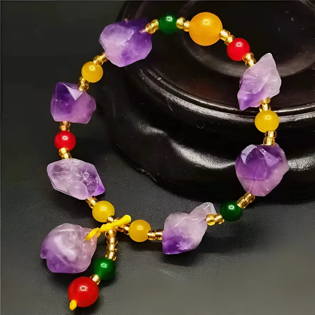 Purple amethyst bracelet with natural shaped beads and a fu character charm on a white background.