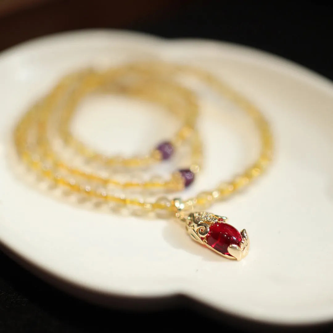 Handmade natural gold rutilated quartz bracelet with three gold circles and a chopsticks charm on a white background.