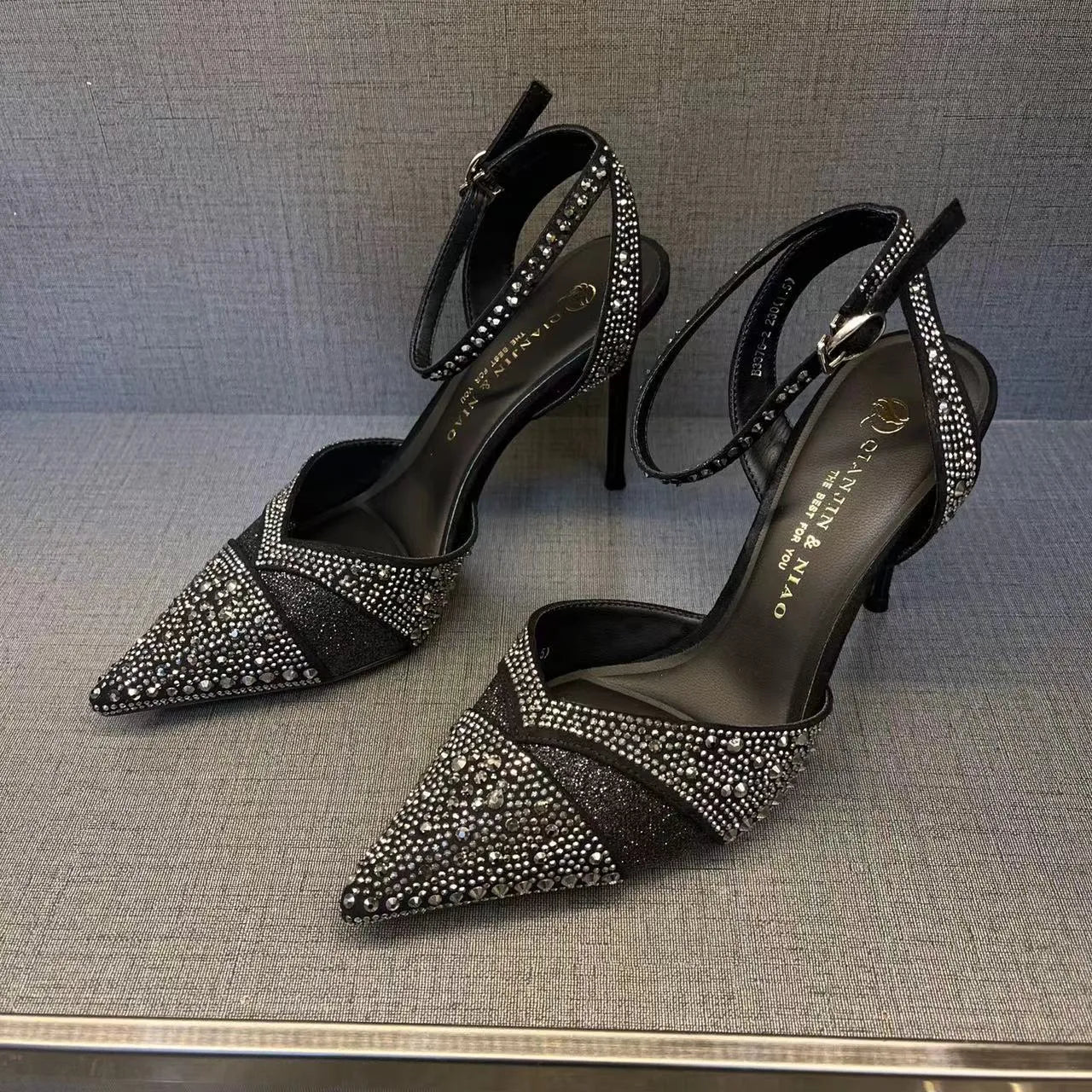 Women's black high-heeled shoes with a red sole, showing stiletto heel and pointed toe design.