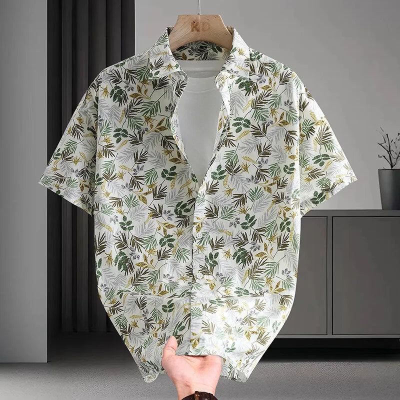 Man wearing a short sleeve cotton Hawaiian shirt with a blue and white floral print.