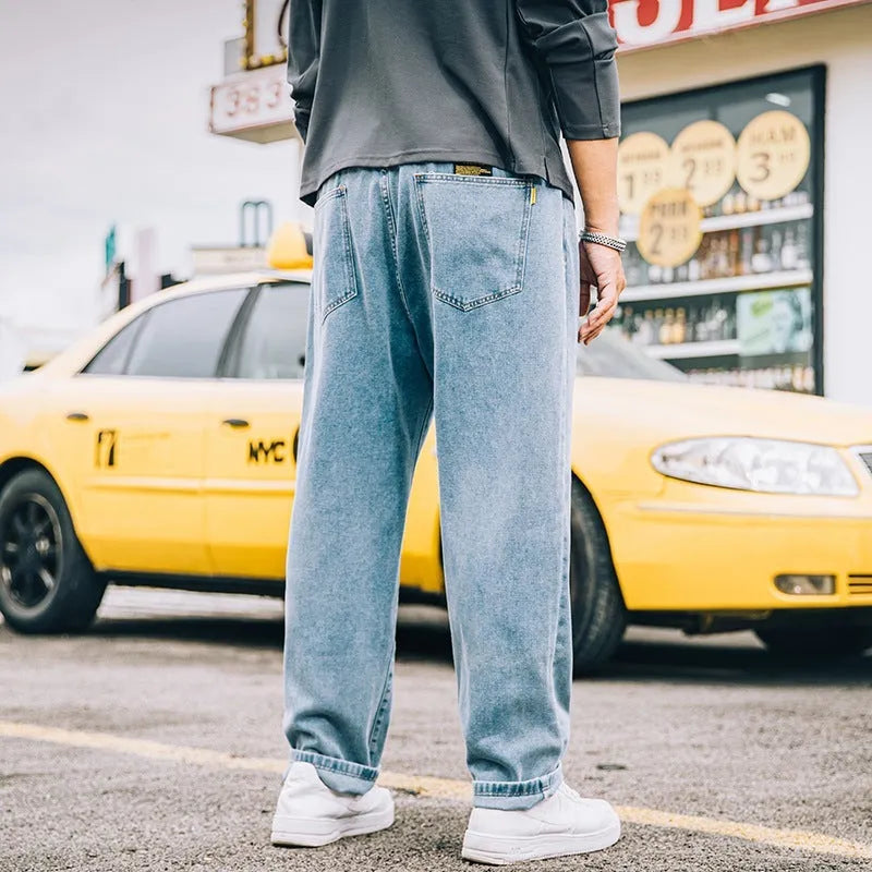 Man wearing dark blue loose straight-leg casual jeans with a mid-waist and zipper fly.