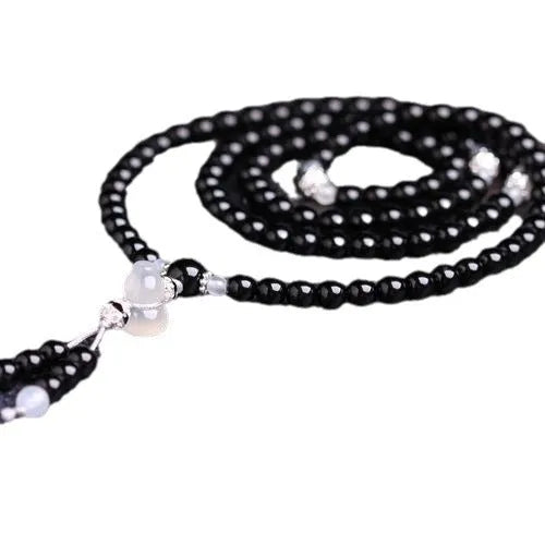 Black agate bracelet with 108 geometric beads and number details on a wrist.