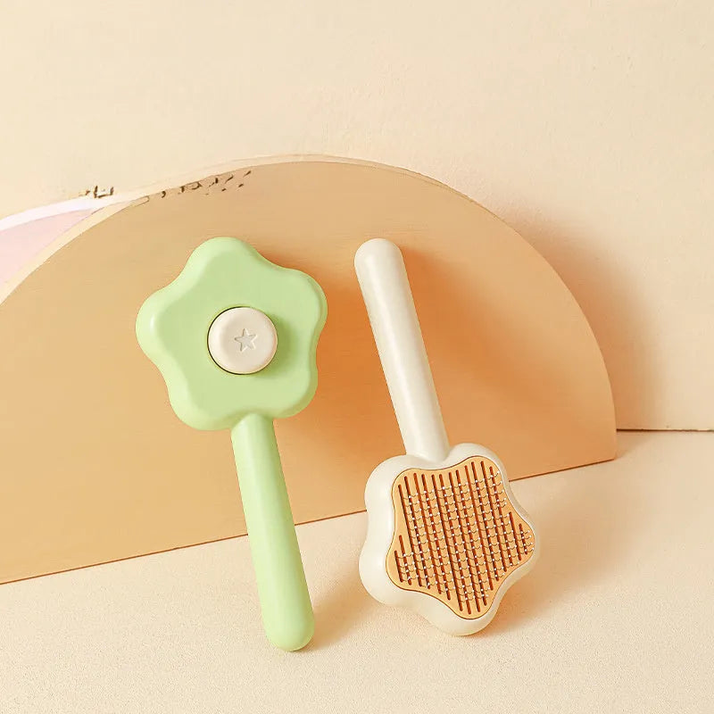 Green and yellow self-cleaning stainless steel cat comb with needle teeth on a wooden table.