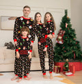 Family wearing matching red plaid Christmas pyjamas with a dog in a matching set.