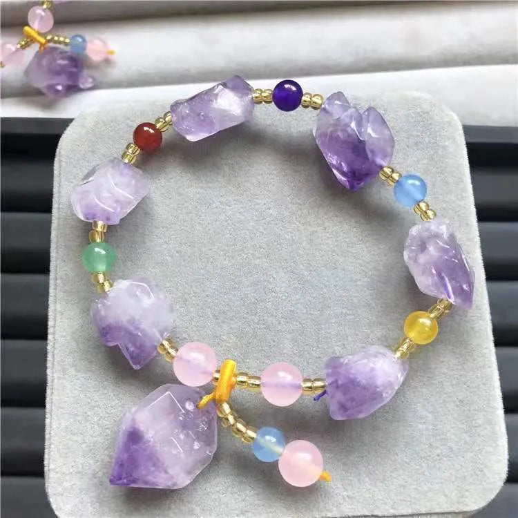 Purple amethyst bracelet with natural shaped beads and a fu character charm on a white background.