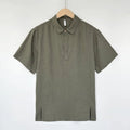 A man's loose-fit linen short-sleeve top in grey green with a V-neck and thin lapels, laid flat.
