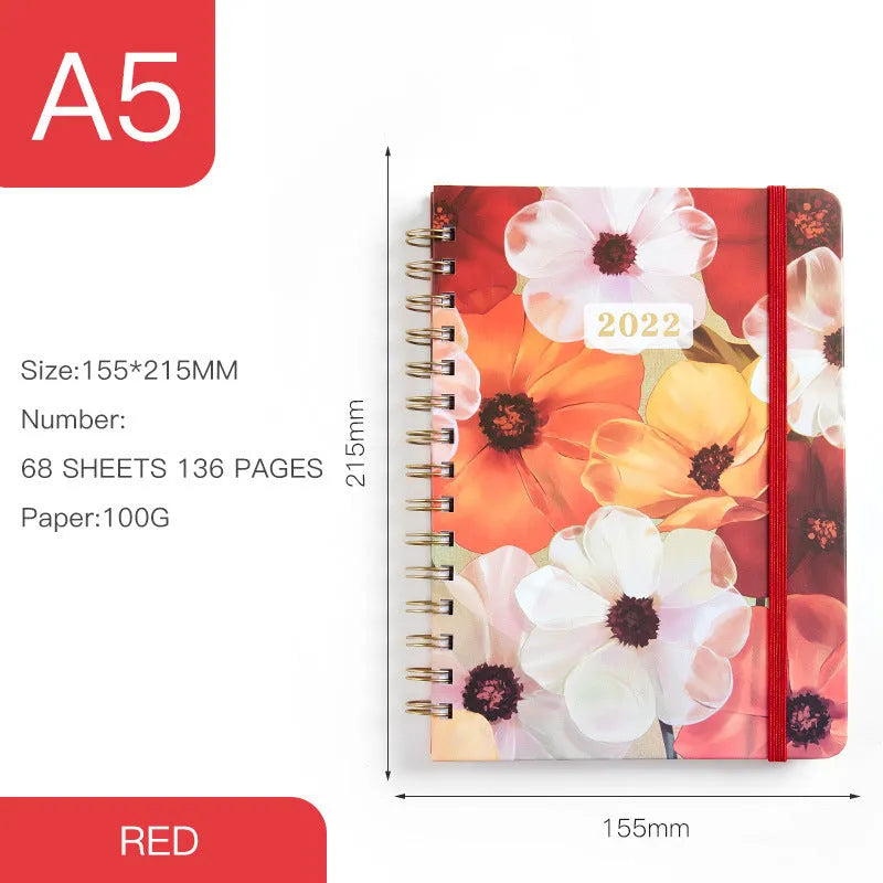 A5 spiral notebook with colourful floral cover, open to show lined pages and metal coil binding