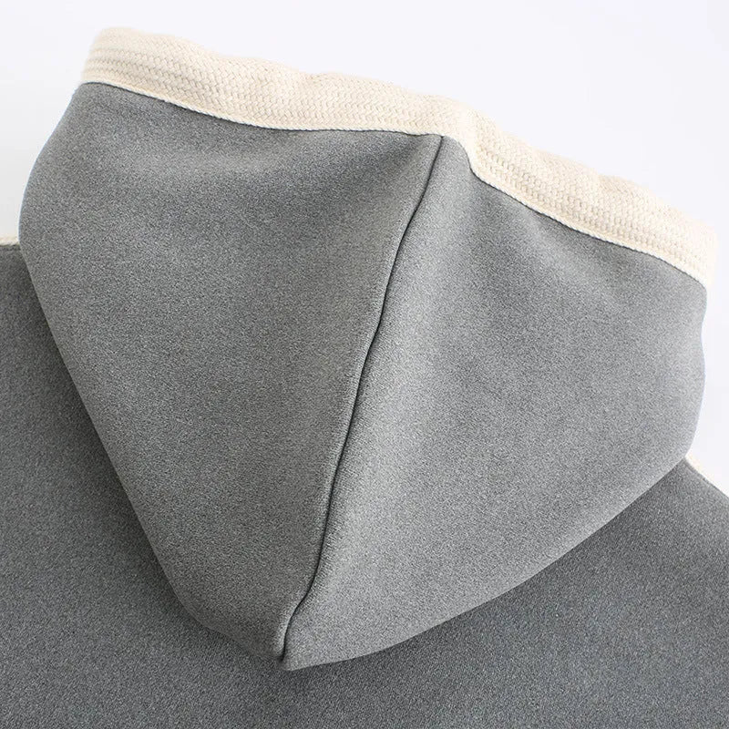 Women's USB heated jacket hoody in black, with brushed fabric and knitted construction, shown outdoors in cold weather