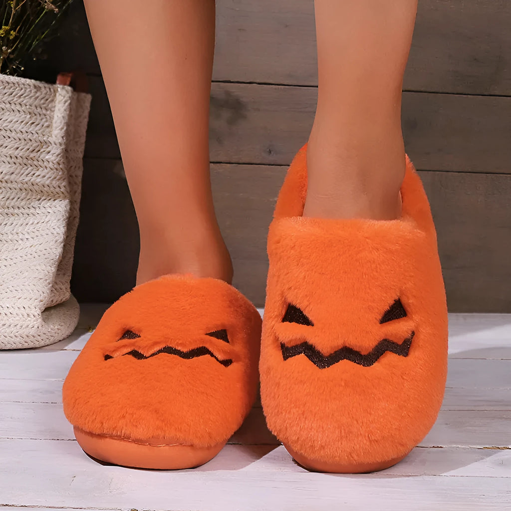 Orange Halloween pumpkin-themed plush slippers with a coral velvet upper and flat heel.