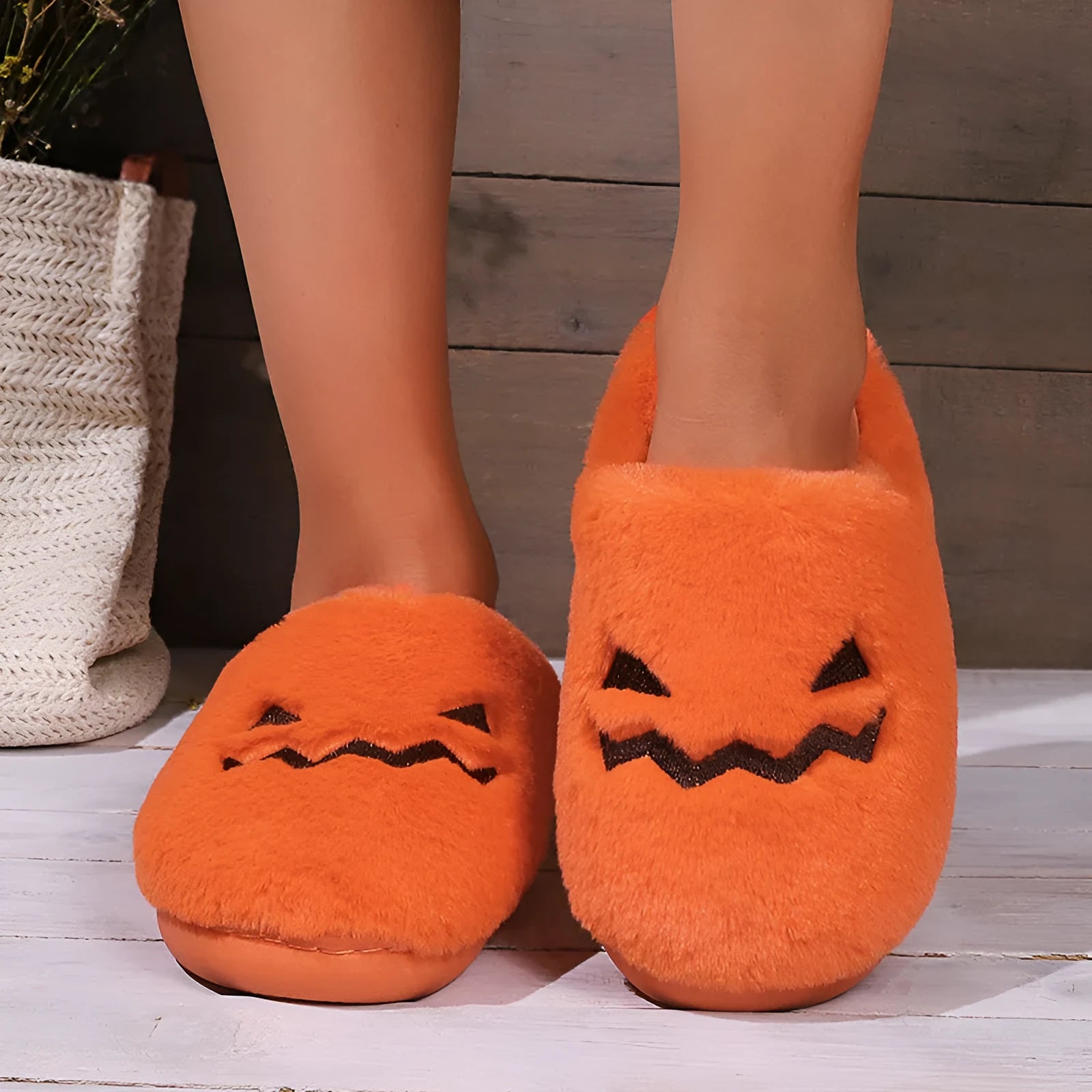 Orange Halloween pumpkin-themed plush slippers with a coral velvet upper and flat heel.