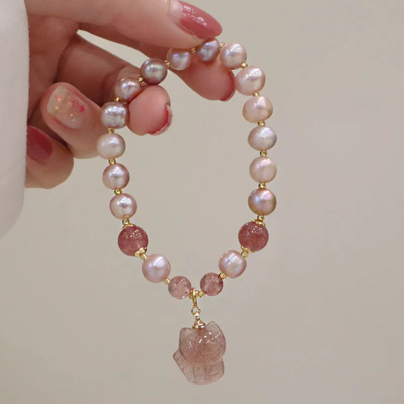 Women's light pink freshwater pearl bracelet with a small fox charm on a natural background.
