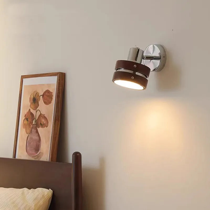 Small Scandinavian-style wall lamp with walnut wood finish, mounted on a wall.