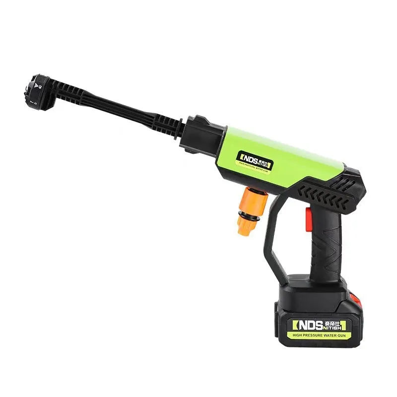 Green wireless high-pressure water gun with metal nozzle and accessories on a table.