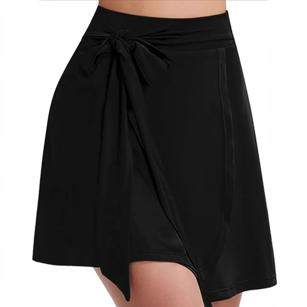 Black thigh-length sports skirt with built-in shorts, high waist, and adjustable shoulder strap on a hanger.