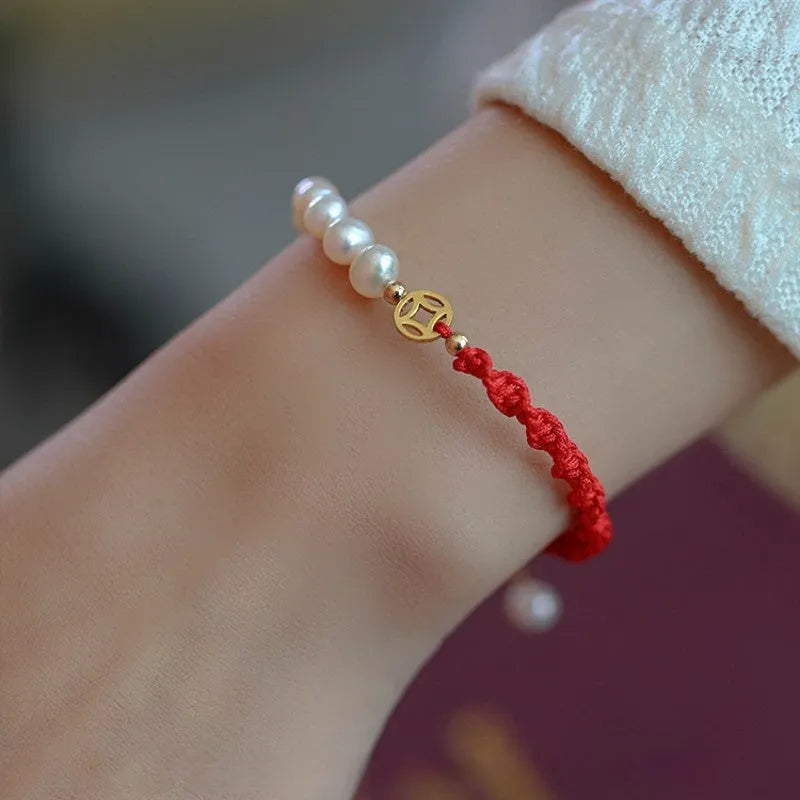Women's pearl bracelet with gold-plated fu charm on braided red rope