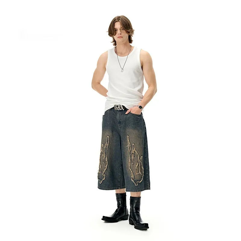 Men's black denim shorts with cropped length and flame embroidery patch design on leg