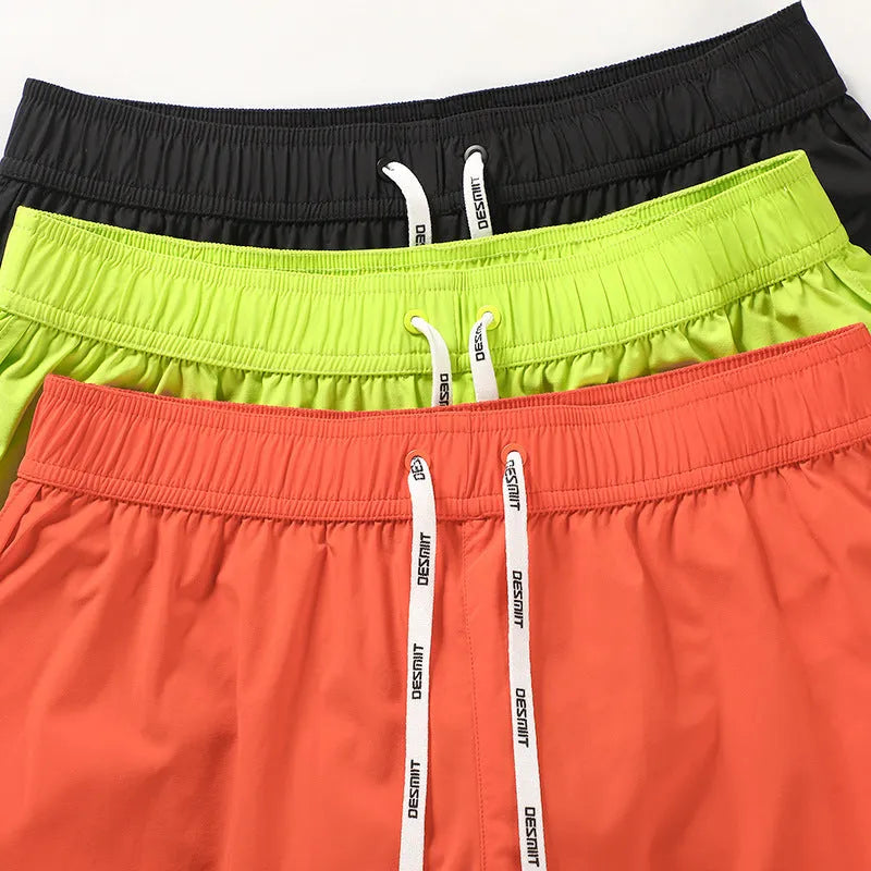 Man wearing loose orange red polyester beach shorts with micro elastic waist