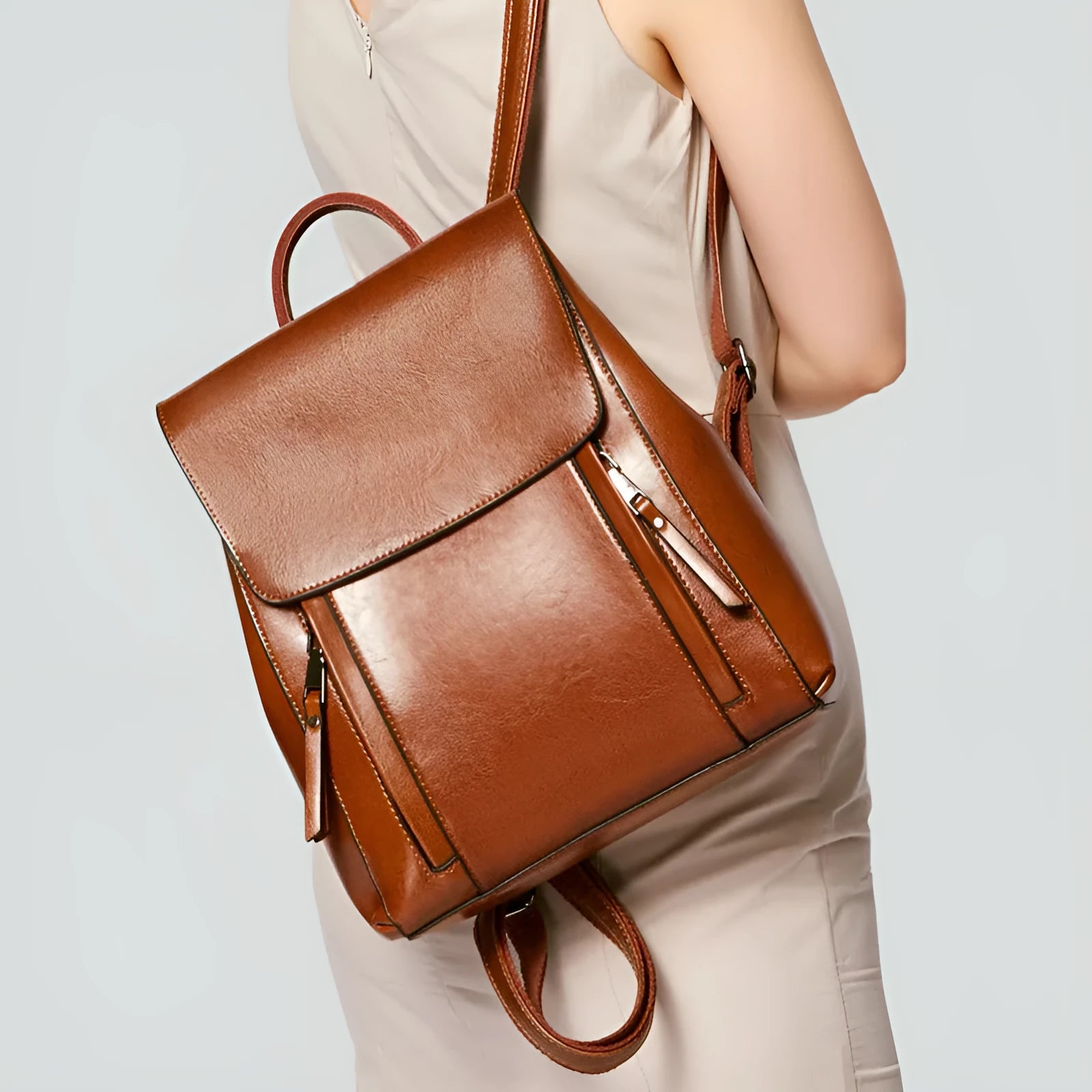 Large genuine cowhide leather women's backpack in black, shown with open cover to reveal internal zipper pockets and phone sleeve.