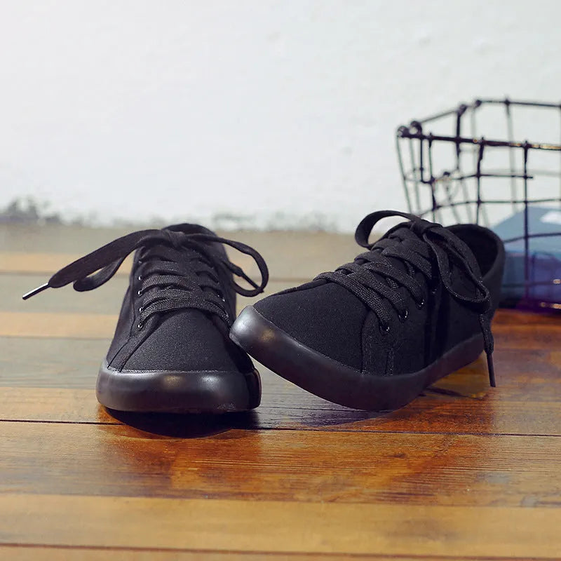 Women's all-black canvas flat lace-up shoes with a slim profile and rubber sole.