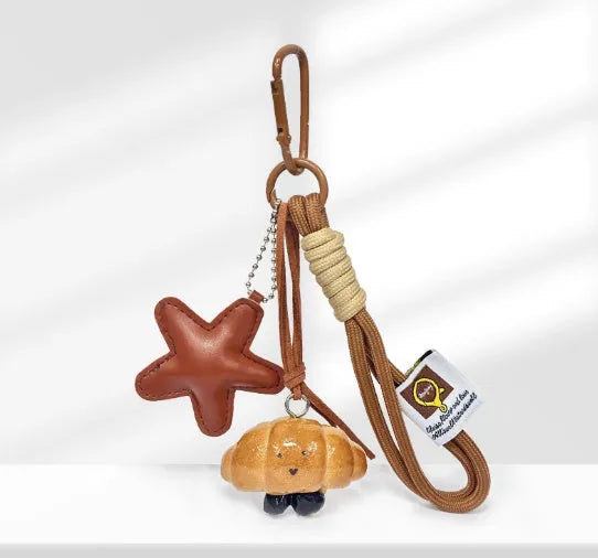 Handmade soda bread handbag charm pendant with cartoon croissant design and brown strap