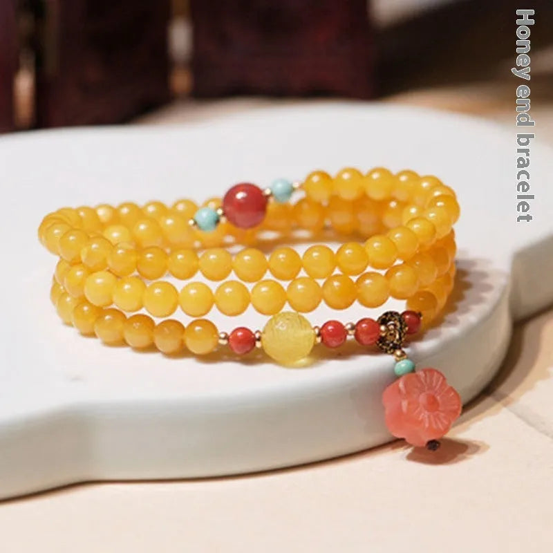 Yellow chicken grease coloured amber bracelet with animal zodiac charm on a white background.