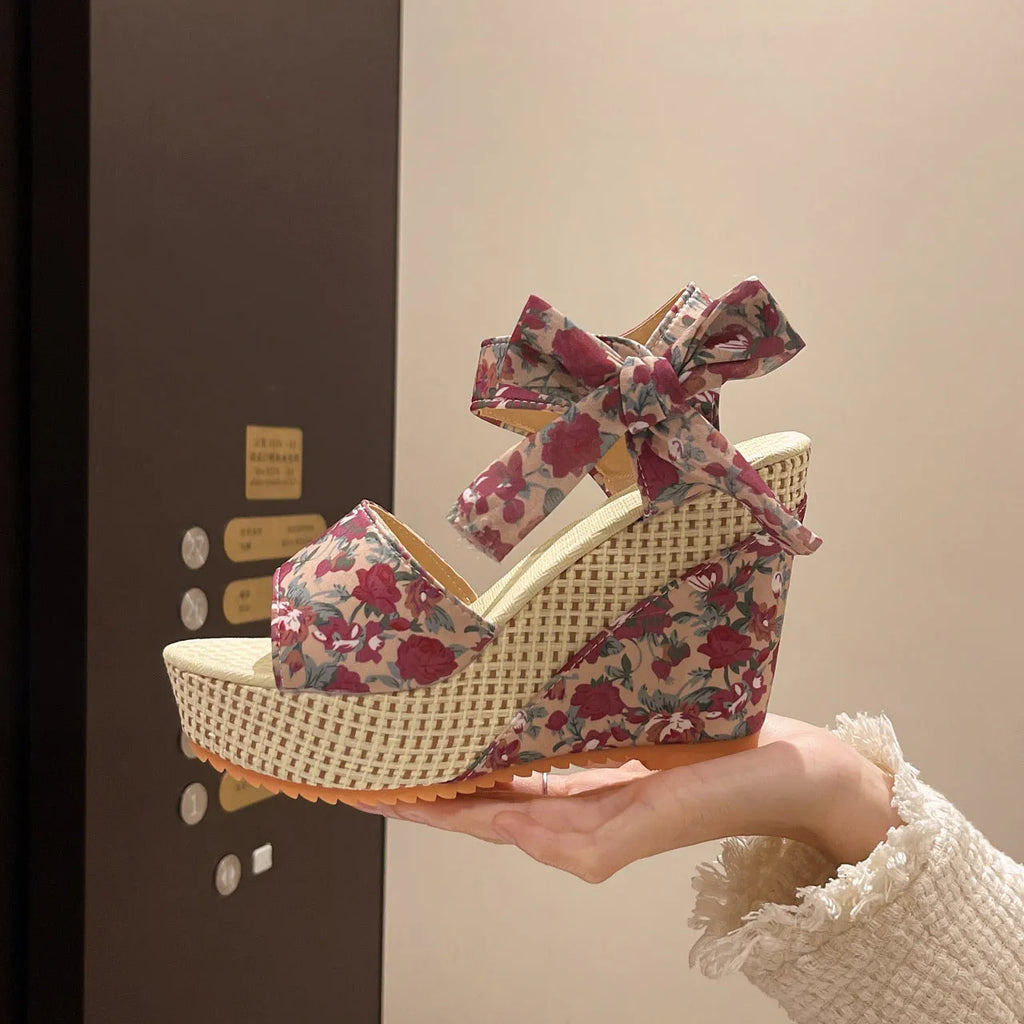 Women's pink floral peep toe wedge sandals with an ankle strap buckle on a rubber sole.