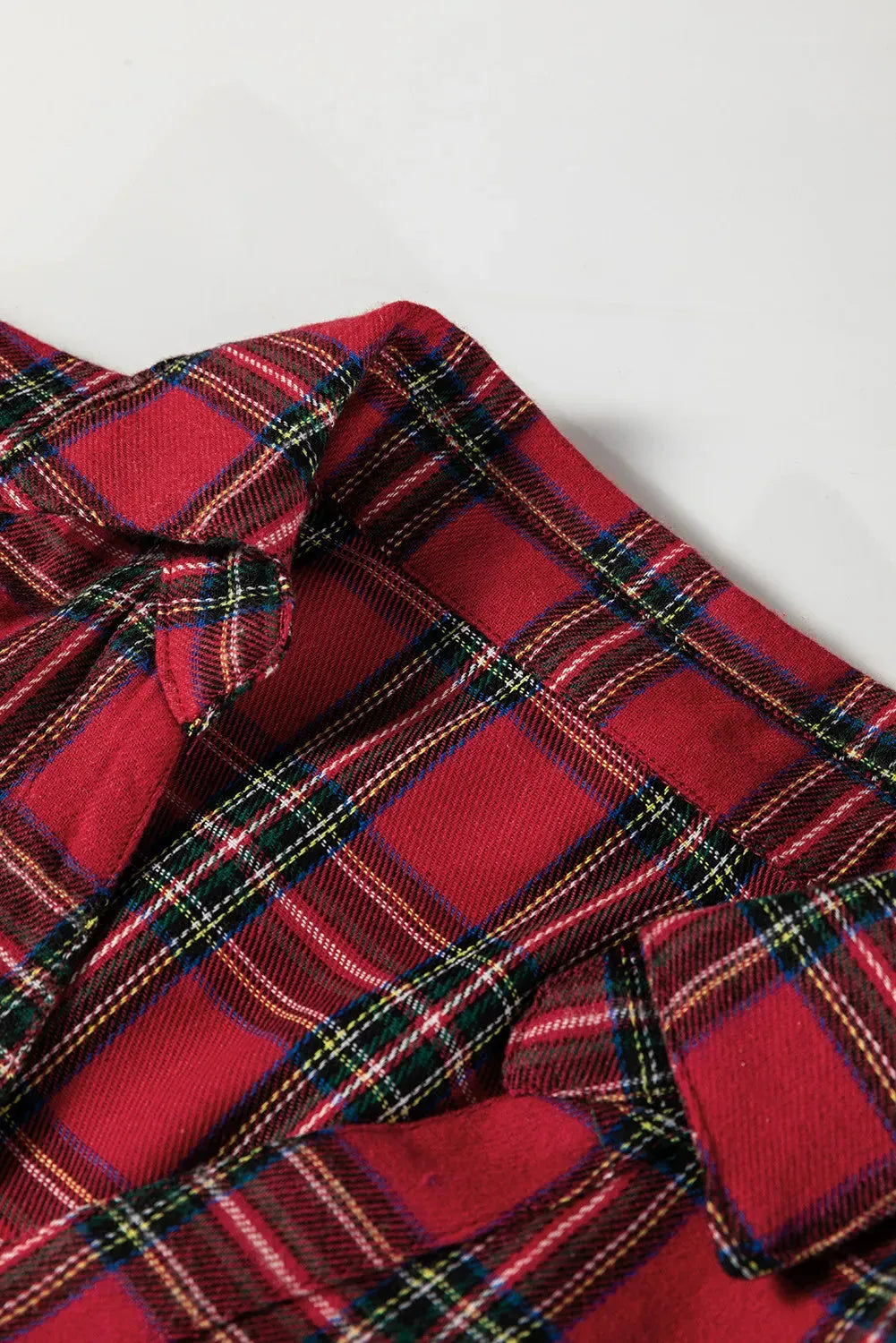 Red plaid mini dress with shirt collar, button front, long sleeves, and ruffle hem detail