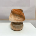 Handmade glass mushroom table lamp in Earth colour on a wooden bedside table with a soft glow