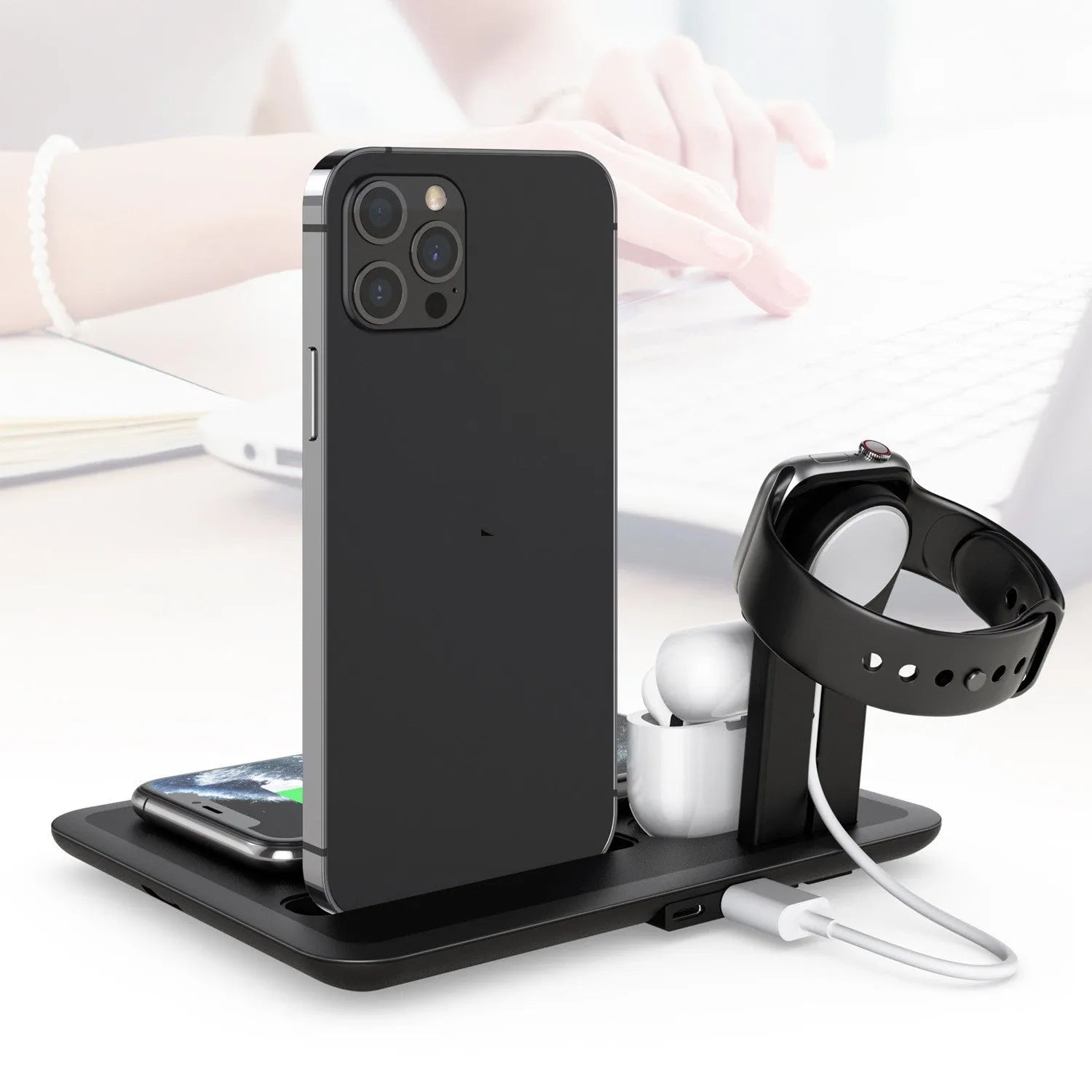 Black and white desktop wireless charging station for phone, headphones, and smartwatch with USB cable.