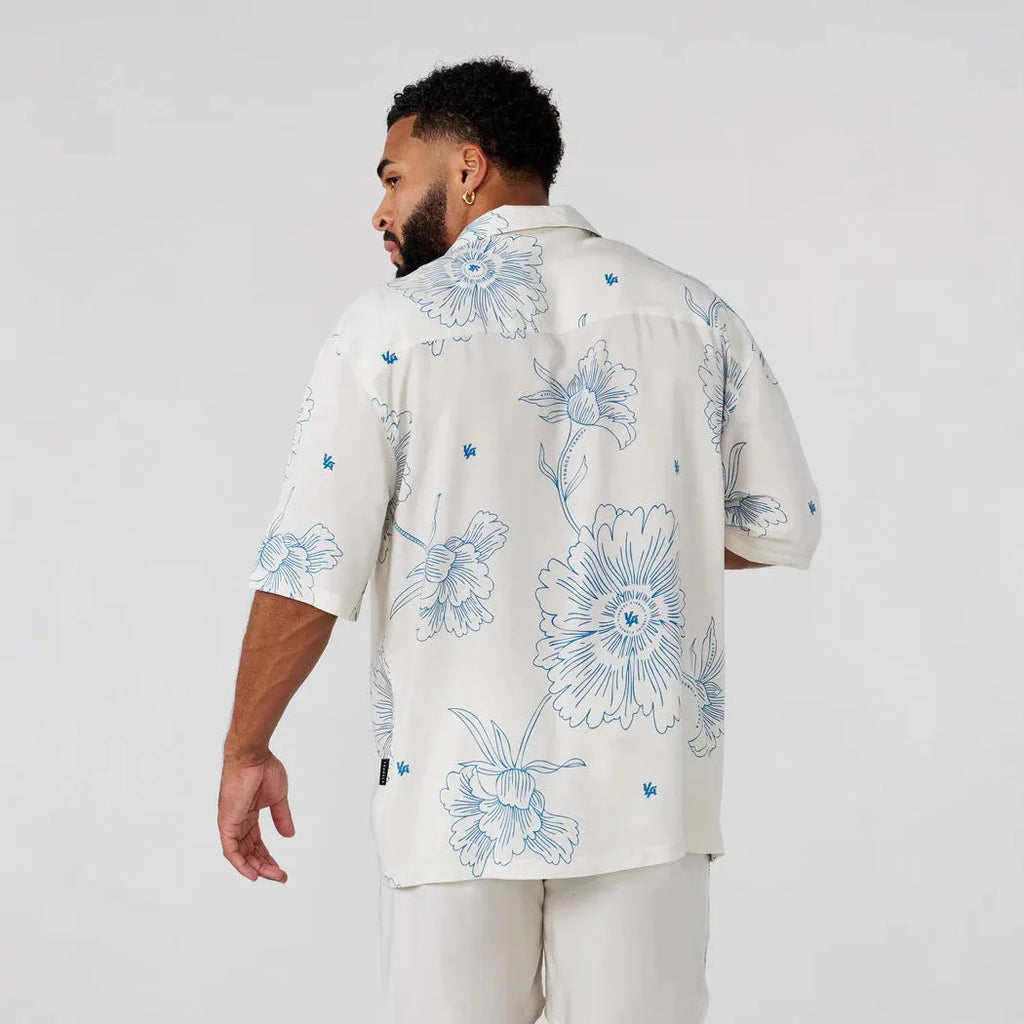 A loose-fitting short sleeve top with a floral print in a light colour, laid flat.