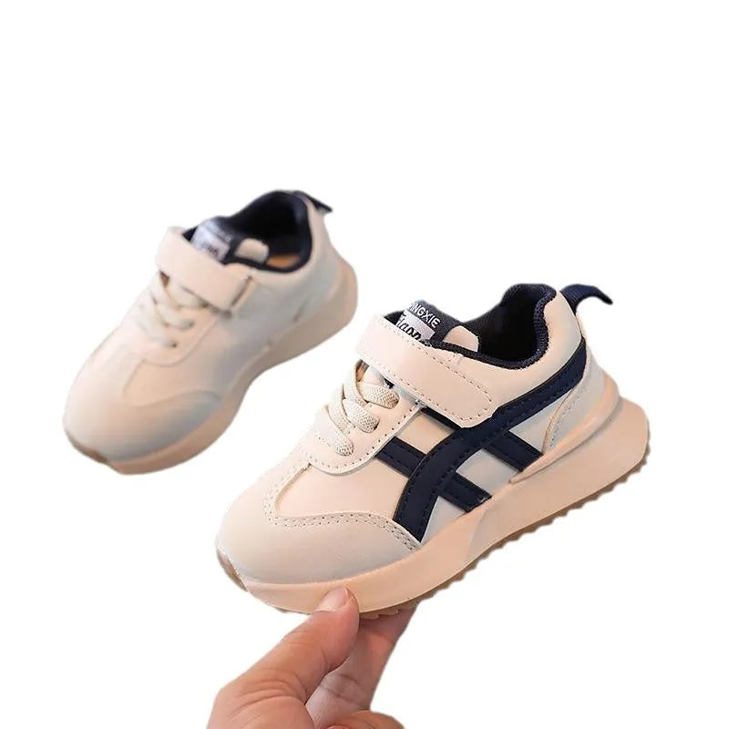 Children's solid-colour sneaker with Velcro strap, shown in beige, on a rubber sole.