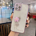 Green iPhone case with a 3D white flower design and a rotating stand on the back.