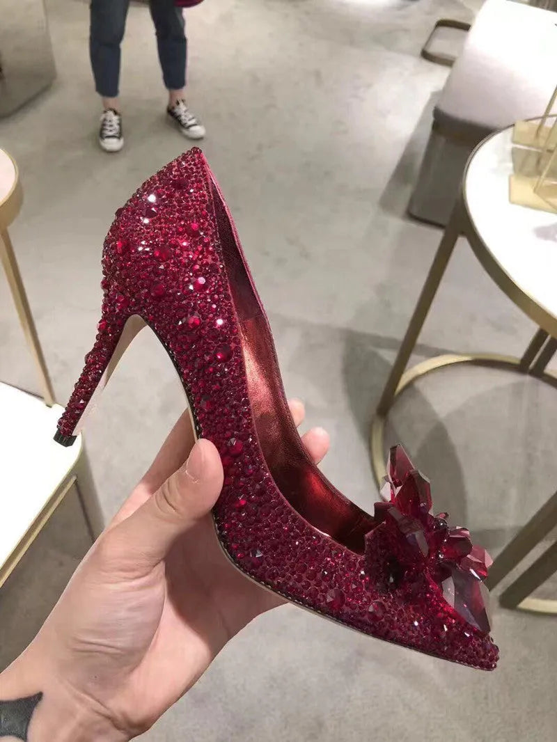 Women's gold stiletto high heel with pointed toe, rhinestone decorations, and a bow.