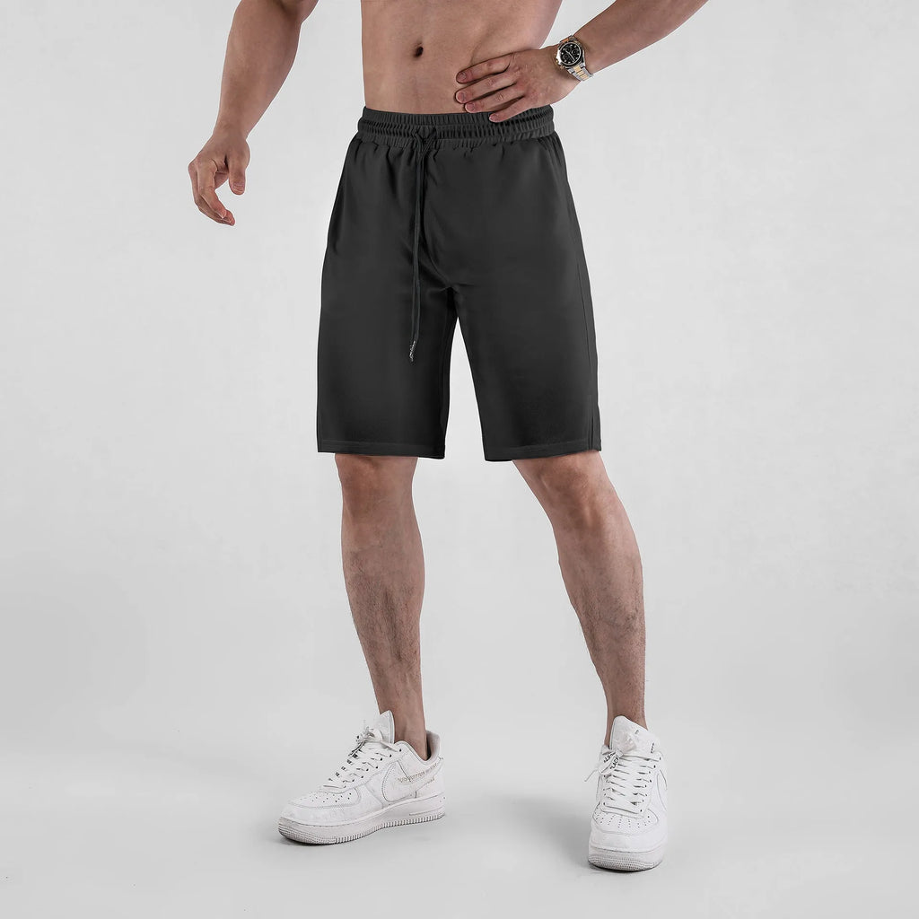 Man wearing black quick-drying mesh fitness shorts with an elastic mid-waist and loose fit.