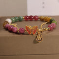 Close-up of an agate butterfly bracelet with a tourmaline-coloured gourd charm on a model's wrist.