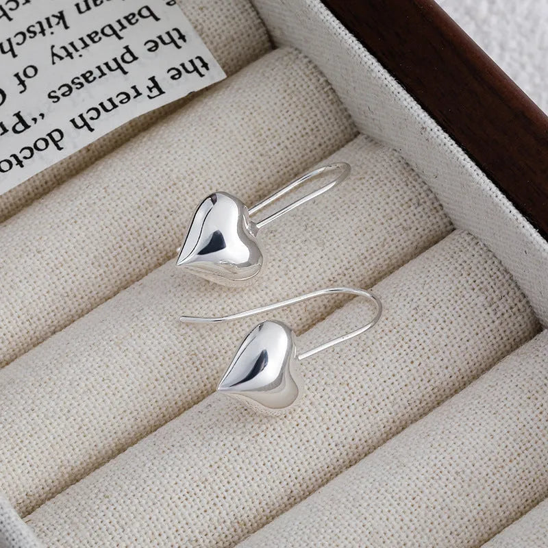 Silver coloured heart-shaped earrings with three-dimensional glossy finish and Korean style design