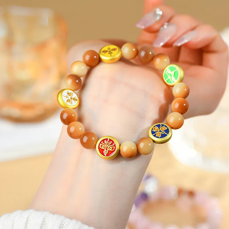 Yellow Bodhi seed bracelet with five directions geometry pattern on wooden surface