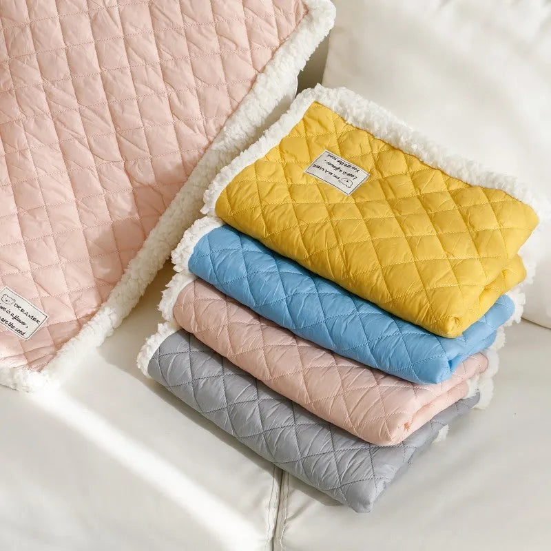 Quilted terry cloth cat blanket in blue, shown on a pet bed.