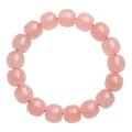 Close-up of a pink natural crystal barrel bead bracelet with geometric shaped beads on a wrist.