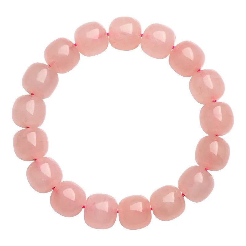 Close-up of a pink natural crystal barrel bead bracelet with geometric shaped beads on a wrist.