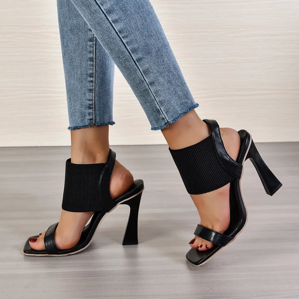 Women's high heel sandals with elastic straps in black, shown from the side.