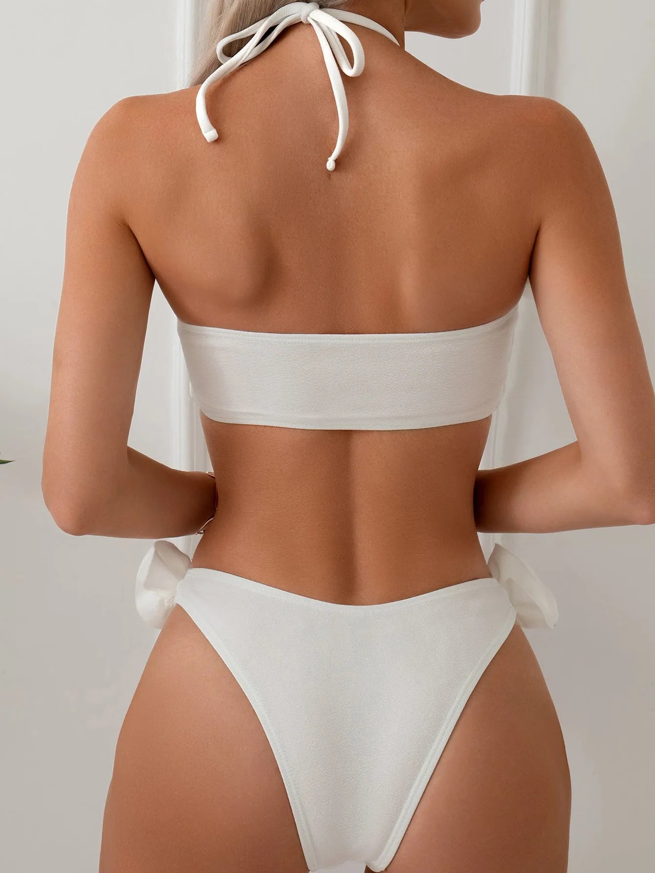 White halter bikini with three-dimensional flower pattern and lace-up detailing